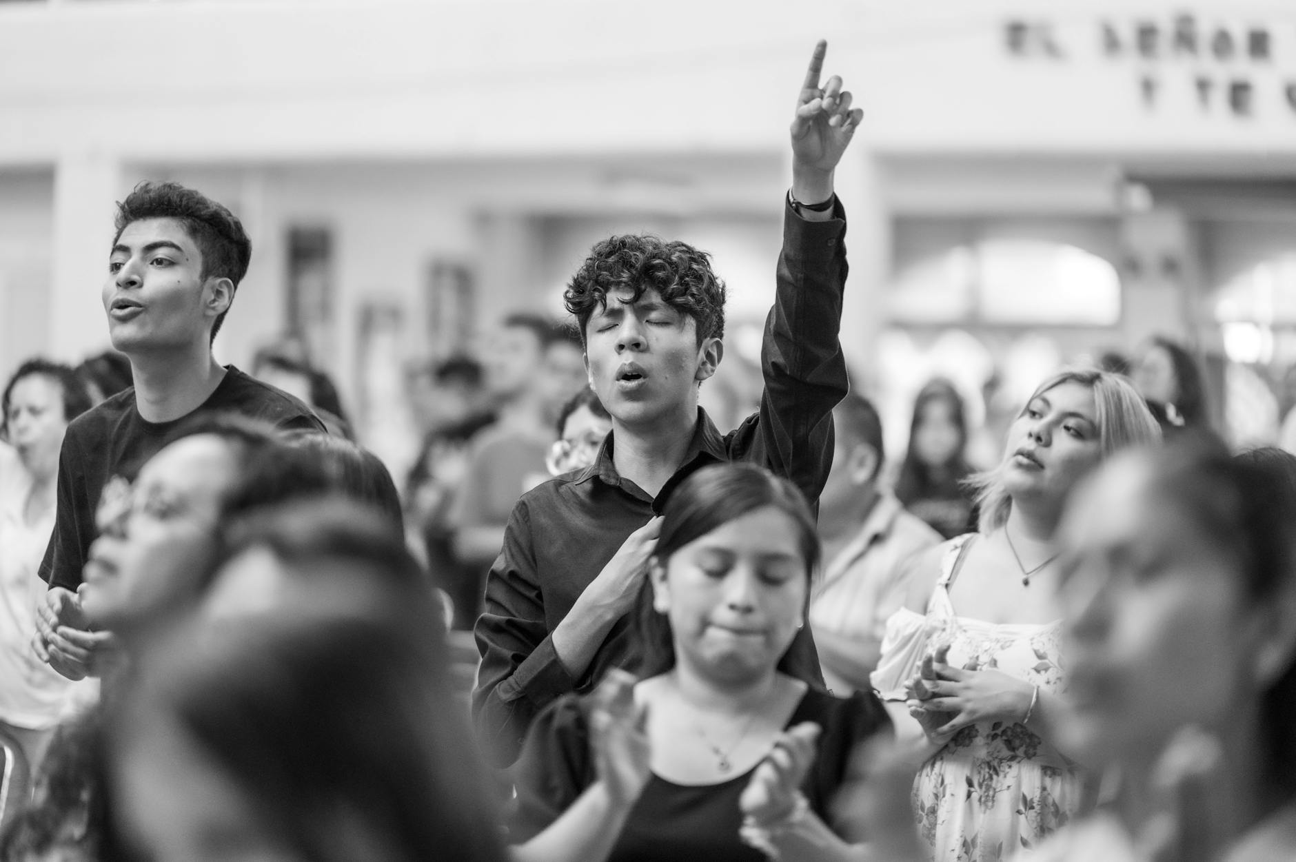 man praying with arm raised among people at gathering